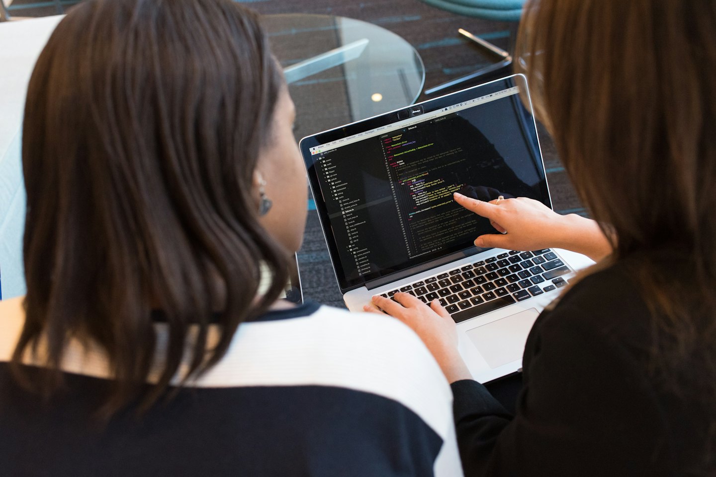 Two people review code on a laptop together.